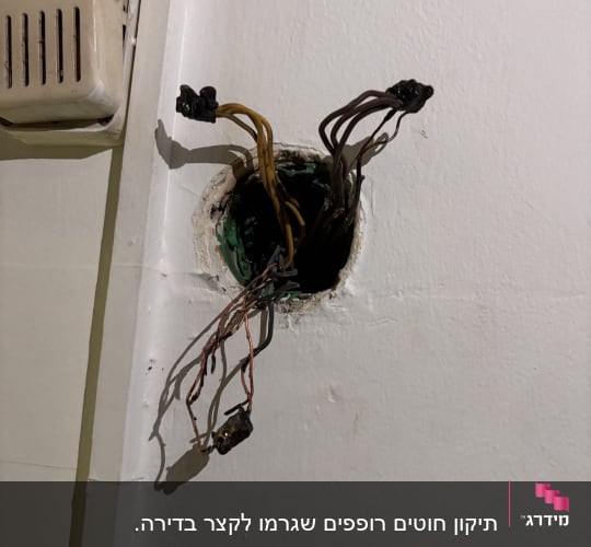 חוטים שרופים ומפויחים בקופסת חיבורים בקיר לאחר קצר חשמלי